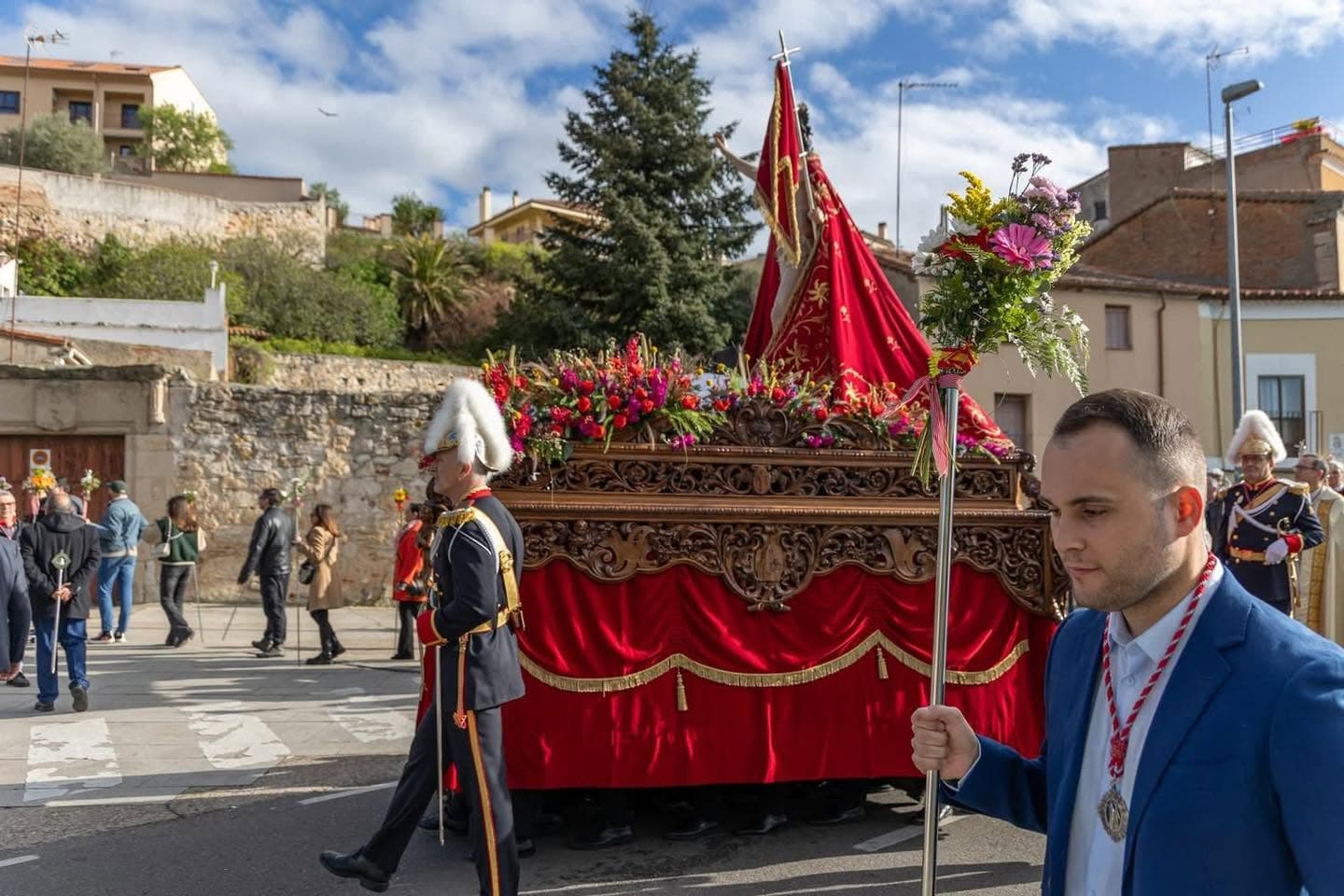 Hermano con la vara florida acompañando al paso por la calzada
