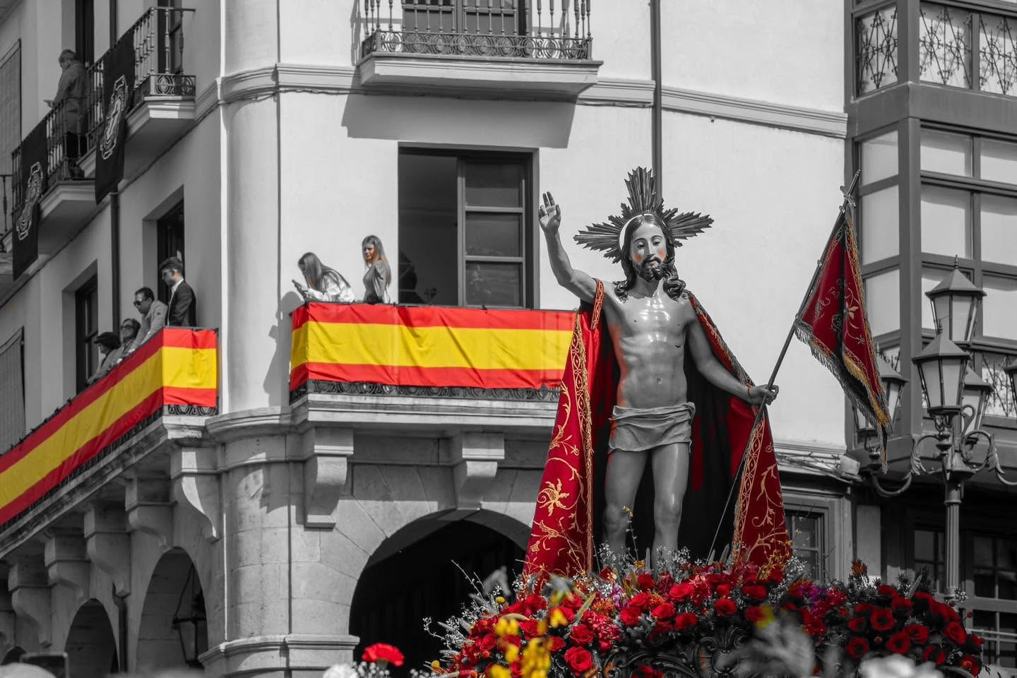 El Resucitado en su paso ante los balcones engalanados con banderas